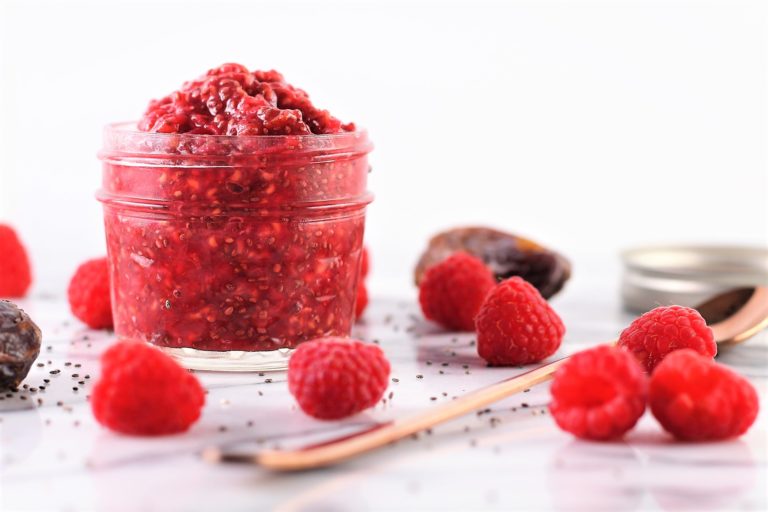 raspberry chia jam in a jar with raspberries on counter