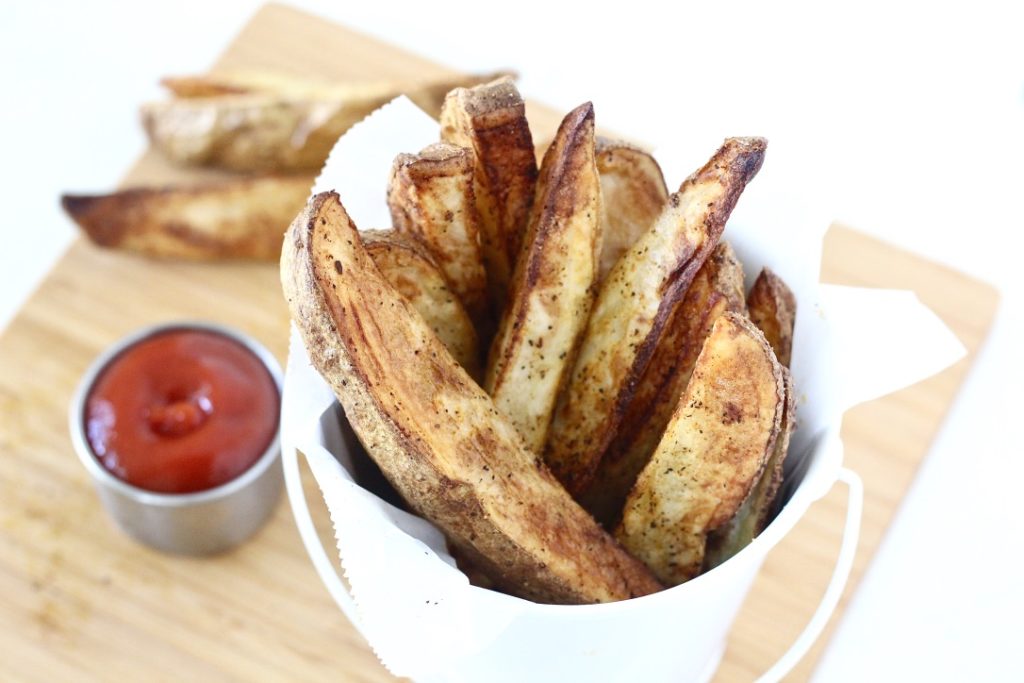 potato wedges in white bucket with ketchup