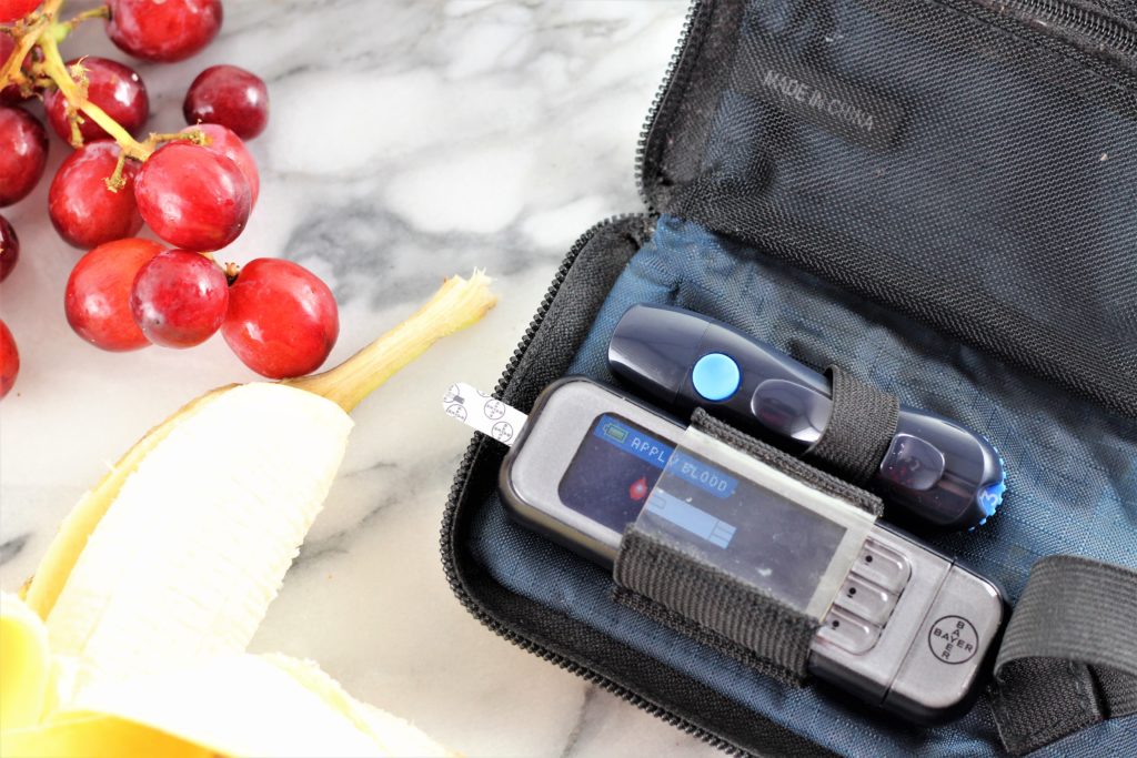 blood glucose meter with bananas and grapes