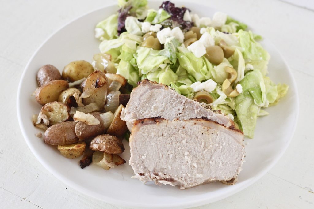 dinner plate with pork loin roast, salad, and potatoes