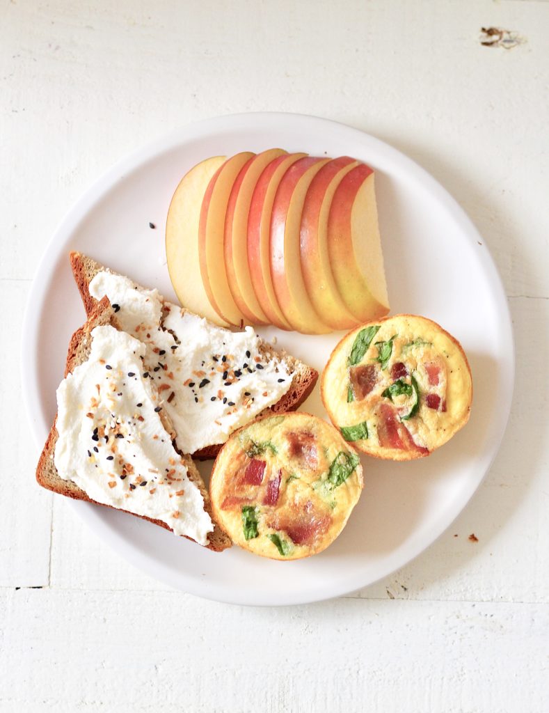 white plate with Starbucks egg bites, toast with ricotta cheese and sliced apples