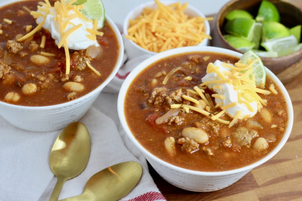 gluten free chili in two bowls with gold spoons