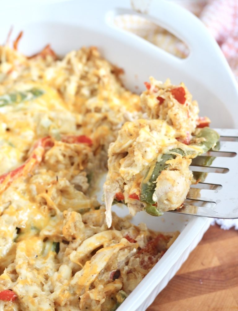 chicken fajita casserole on spatula with white baking dish