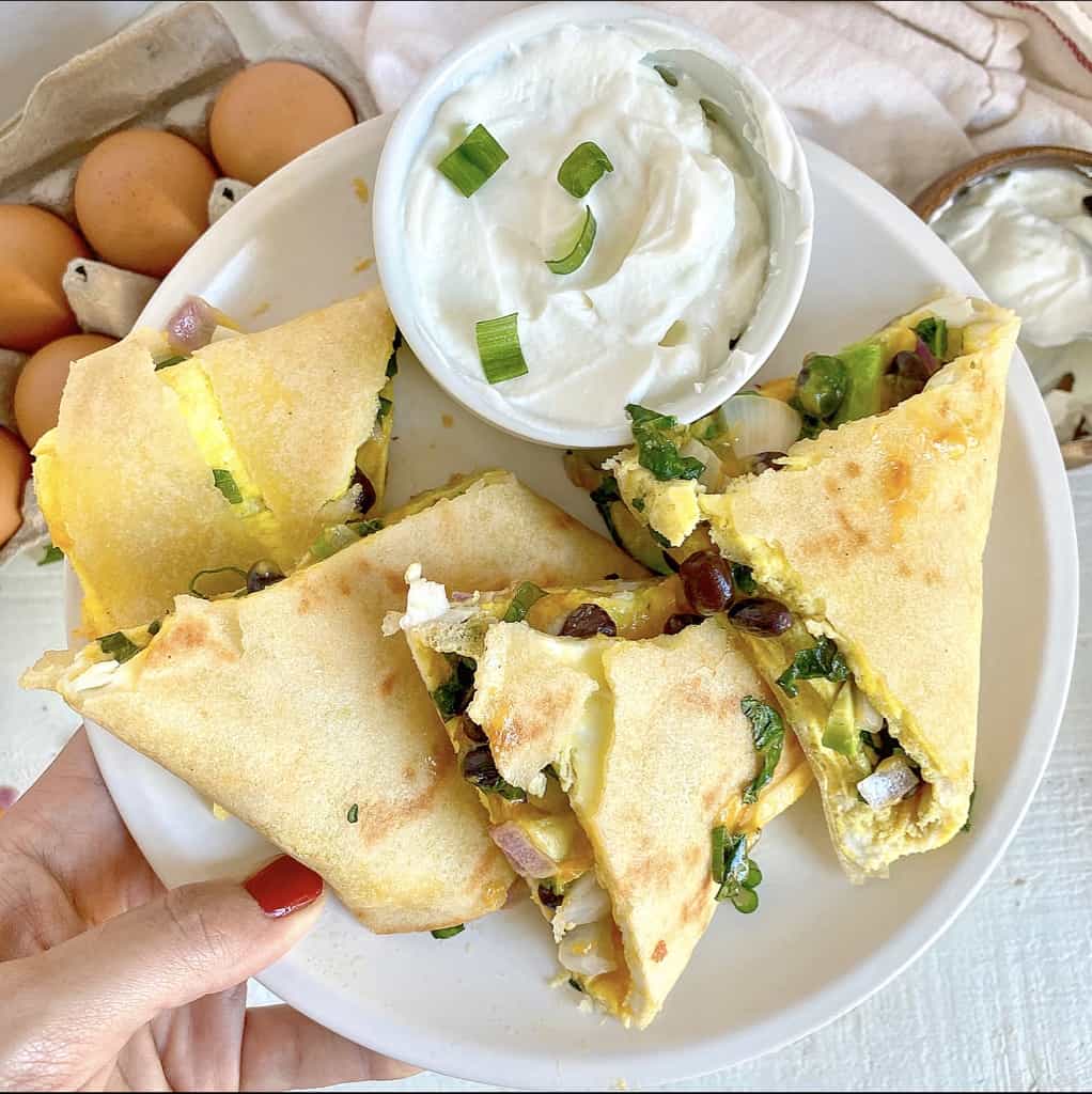 veggie and egg quesadilla with black beans on white plate with plain greek yogurt