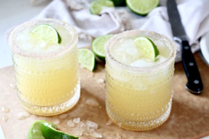 two skinny margaritas with lime wedges on cutting board