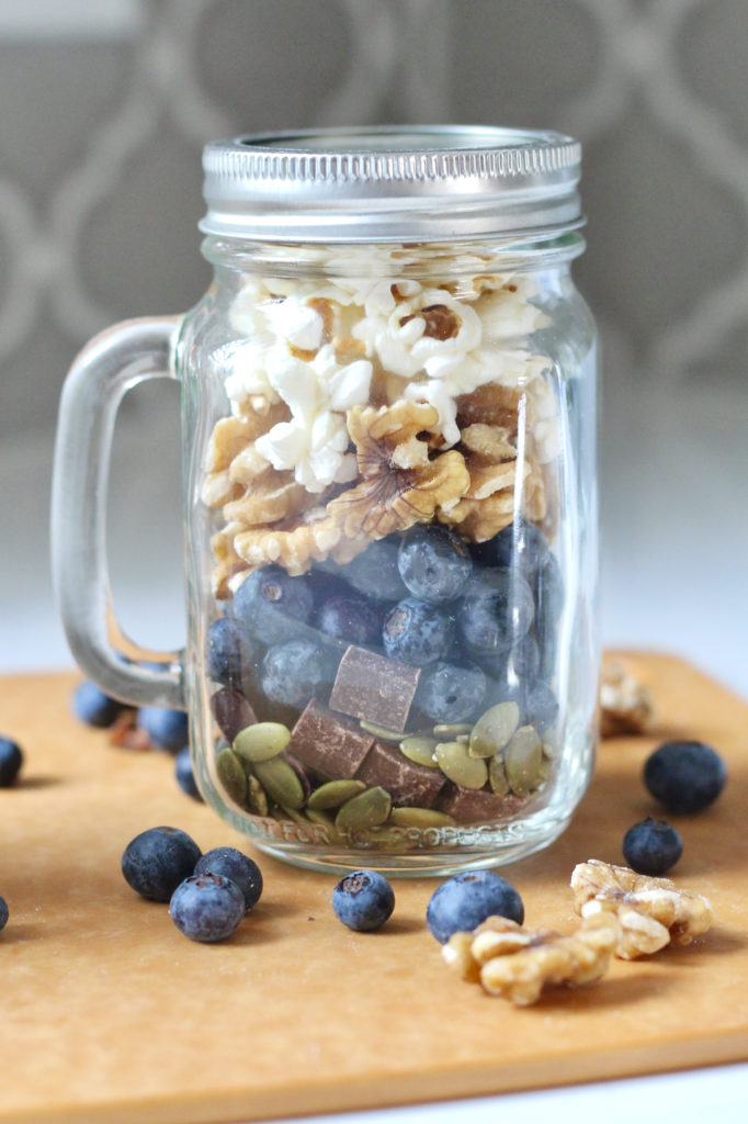 homemade trail mix in mason jar with blueberries walnuts and popcorn