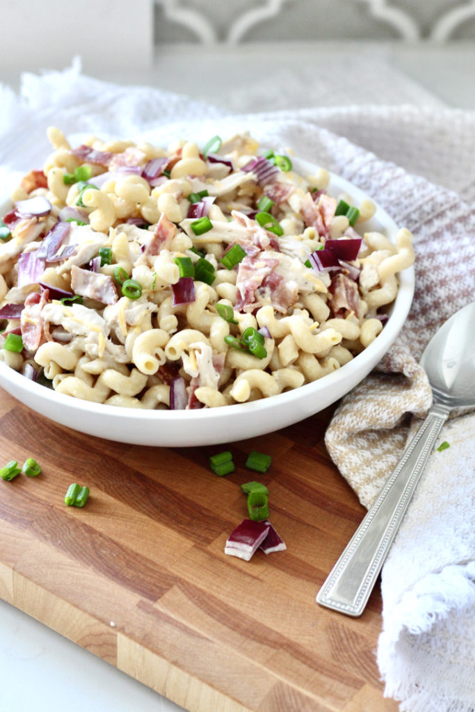 chicken bacon ranch pasta salad in white bowl on wood cutting board