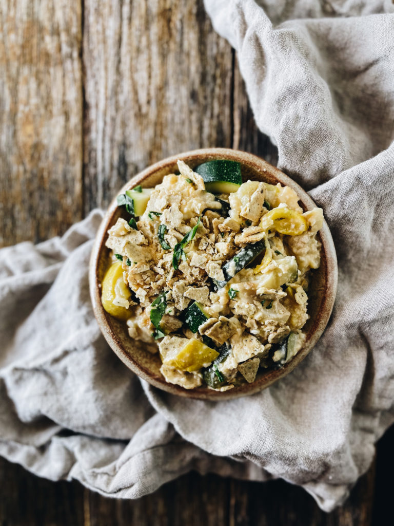 zucchini and squash casserole in round dish on wood board