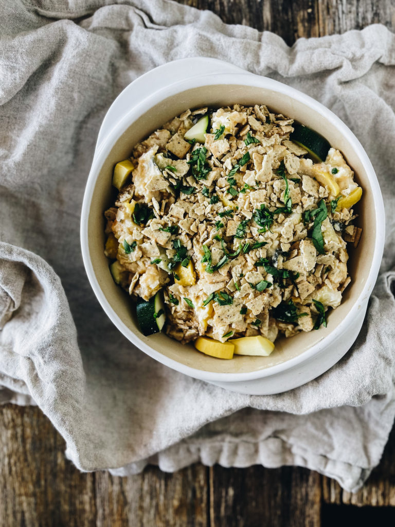 zucchini and squash casserole with cheese in white round dish