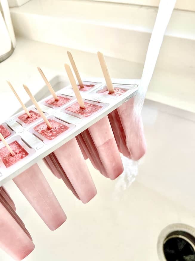 pineapple cherry popsicles in popsicle mold with running water