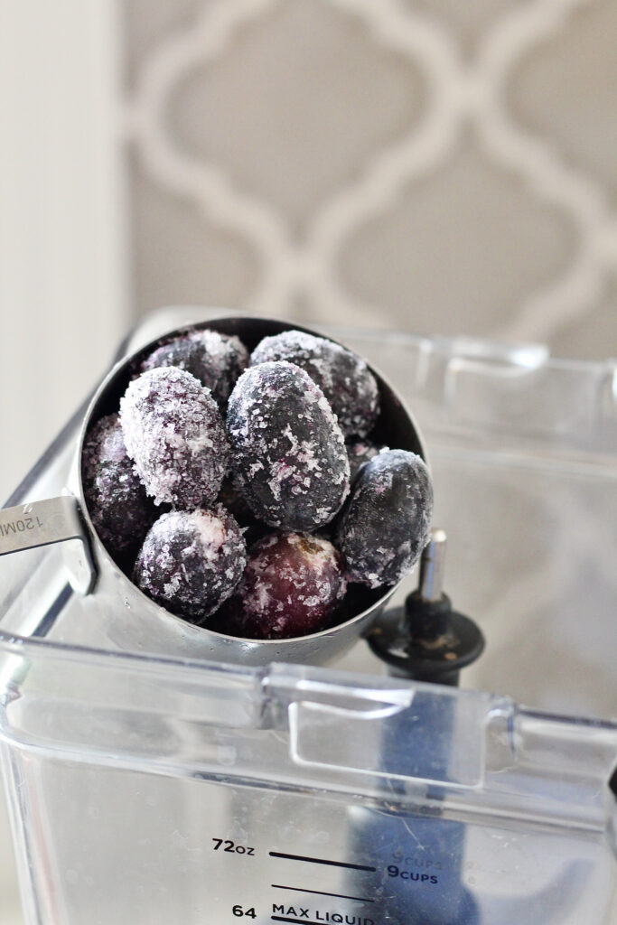 adding frozen grapes to blender for grape smoothie